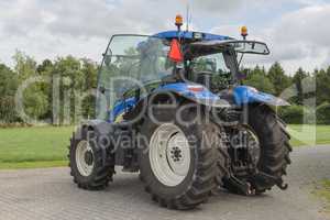 Modern blue tractor on a farmyard.