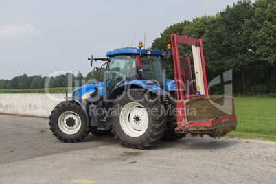 Blue tractor with a red bale slicer.