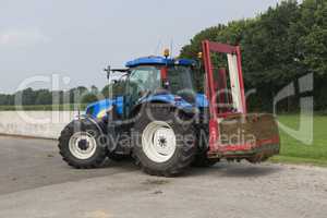 Blue tractor with a red bale slicer.