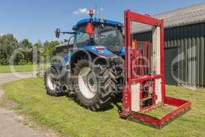 Blue tractor with a red bale slicer.