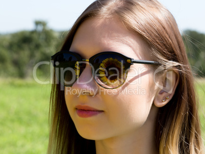 young woman in sunglasses on the nature, sunflower reflected in glasses