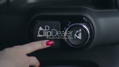Woman hand pushing reverse gear button in car