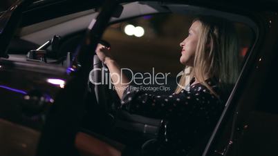 Woman sitting in car making dance moves at night