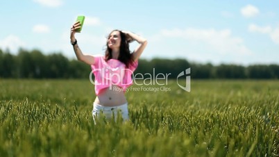 young woman making selfies in green wheat field