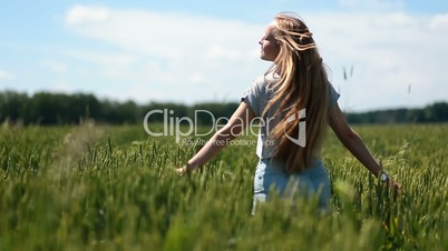 Cute girl walking on green field with open arms