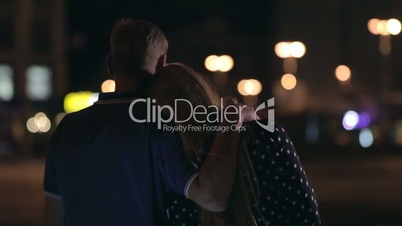 Man hugging woman over night city background