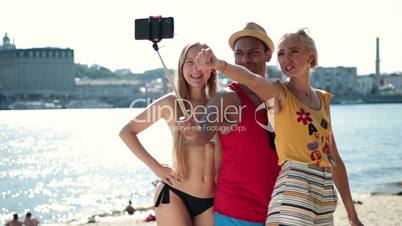 Group of smiling friends making selfie on beach