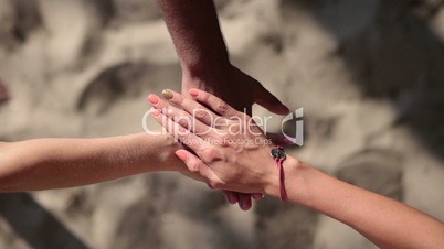 Young people making a stack of hands on the beach