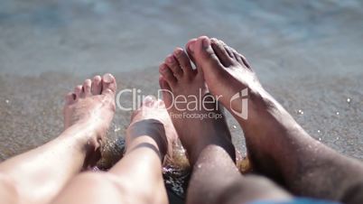 Closeup of couple's feet relaxing on the beach