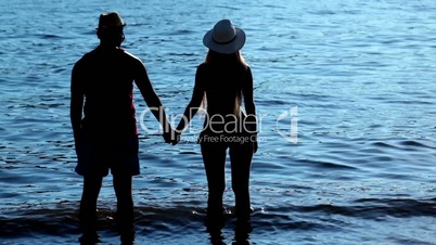 Silhouette couple holding hands at sunset on beach