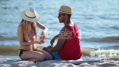 pretty woman applying sunscreen on man's shoulder