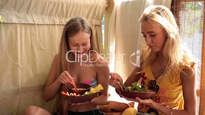 Two attractive girls on vacation eating vegan food