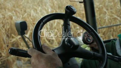 In the cab of combine harvester gathering corn