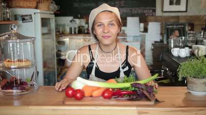 Female chef showing vegetables on cutting board