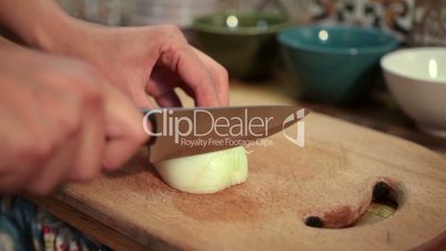 Closeup woman hands slicing onion on cutting board