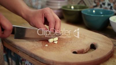 Woman hands chopping fresh garlic with knife