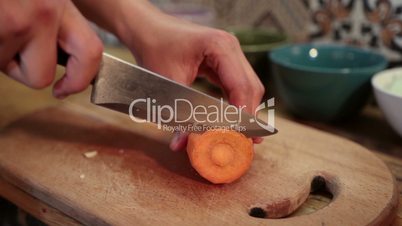 Woman hands slicing carrot on cutting board