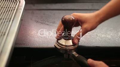 Barista using a tamper to press ground coffee