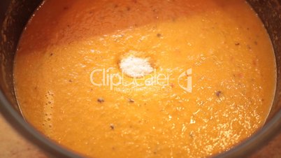 Woman's hand adding salt and spices into soup