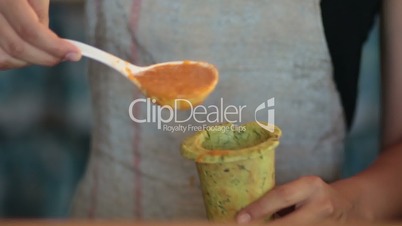 Woman pouring hot vegetable soup into baked cone