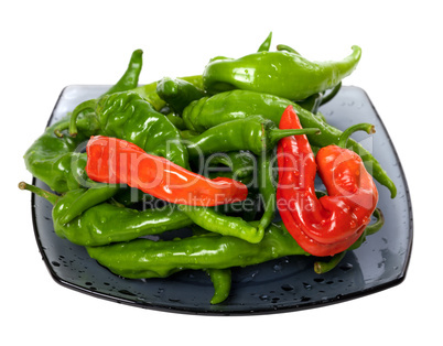 Green and red chili peppers on glass plate