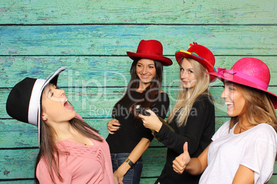 4 Mädchen mit Damenhüten vor einer Fotobox - Mädchen zeigen Daumen hoch