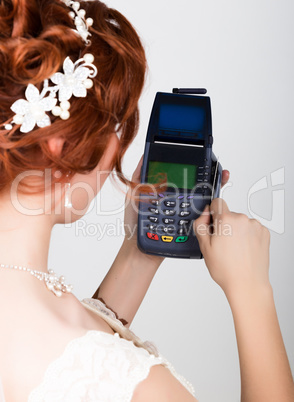 The concept of electronic payment. Closeup a beautiful bride holding credit card over pos terminal