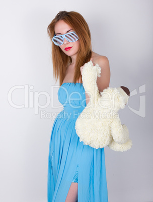 girl in a blue dress and sunglasses in the style of disco, hugging  teddy bear in the same glasses