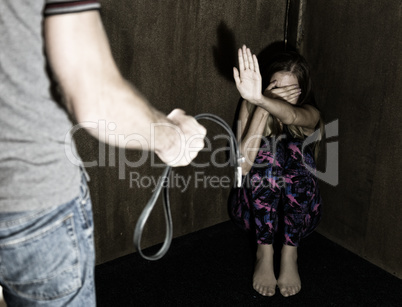 frightened woman sitting in the corner with a faceless man holding belt, conceptual shoot portraying process and effects of domestic violence