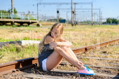 Sad young girl sitting lonely on rail track