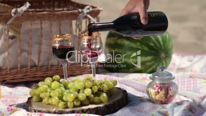 Red wine pouring in crystal glasses on picnic