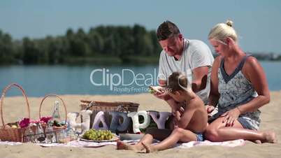 Family with child enjoying picnic on river bank