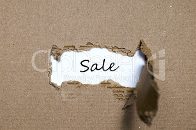 The word sale appearing behind torn paper