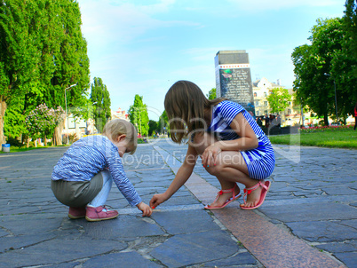 little sisters write on the road in the park