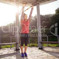 Young beautiful woman doing fitness training with suspension straps.