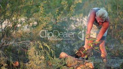 Woman cutting a log into sections with chainsaw