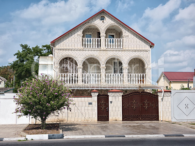 light brick two-storey house with iron gates