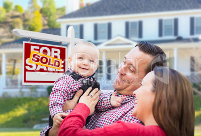 Young Family In Front of For Sale Sign and House