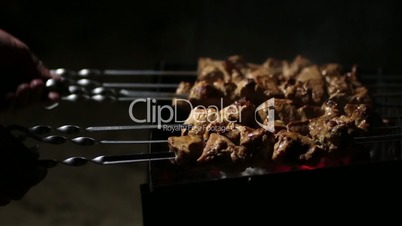 Female cooking meat skewers on the barbecue coals