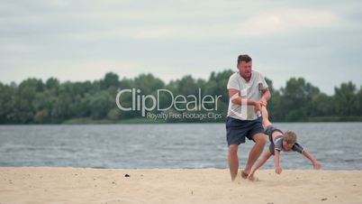 Happy father and son playing on summer beach