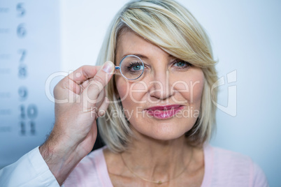 Optometrist examining female patient through magnifying glass