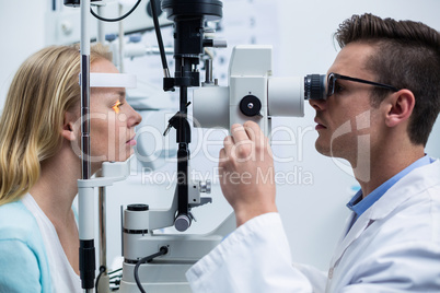Optometrist examining female patient on slit lamp