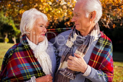 Senior couple embracing with a cover on their shoulder