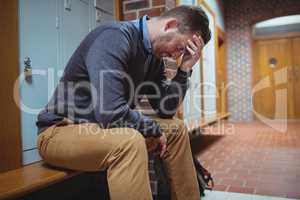 Stressed mature student sitting in locker room