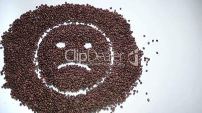 Sad smiley made of coffee beans becoming happy