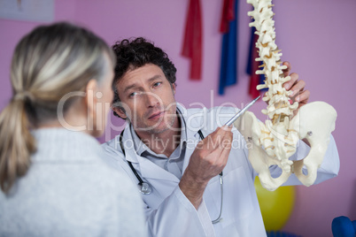 Physiotherapist explaining the spine model to patient