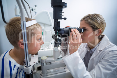 Female optometrist examining young patient on slit lamp