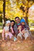 Happy family sitting at park during autumn