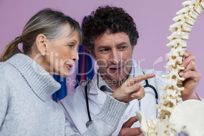 Physiotherapist explaining the spine model to patient