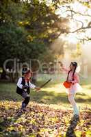 Side view of playful siblings wearing costumes at park